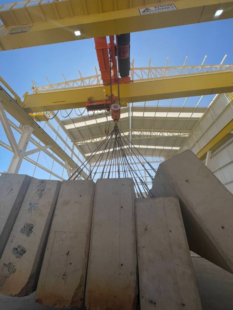 Ponte rolante industrial da Atriumetal içando vigas de concreto pré-moldadas em galpão